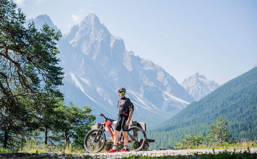 Mountainbiker mit rotem Rad vor Alpenpanorama im Sommer