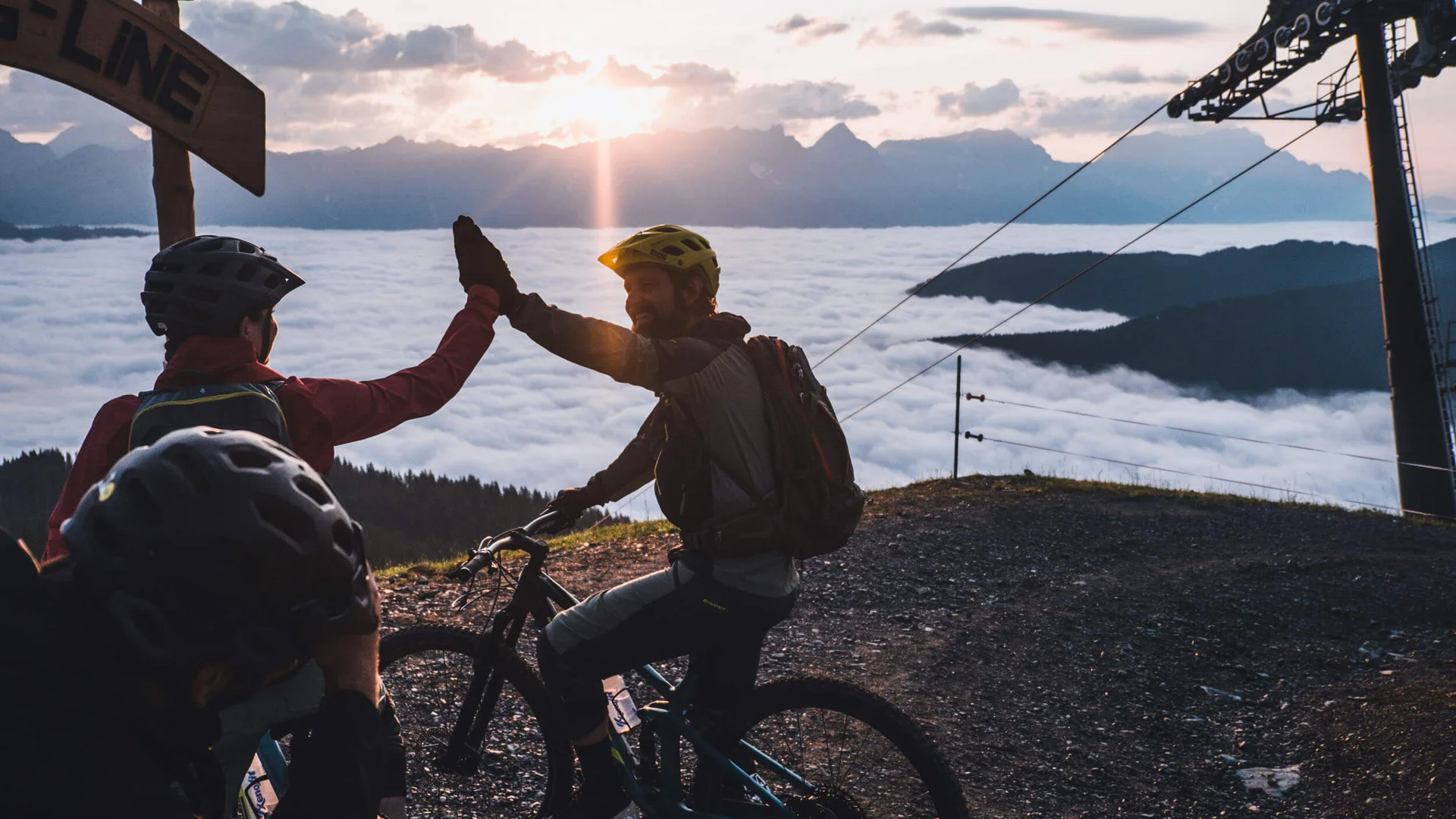 Hotel Rupertus: Ein Retreat für Yogis und Biker © David Karg Mountainbiker geben sich Gipfel-High-Five bei Sonnenuntergang über Nebelmeer