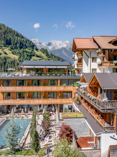 Modernes Hotel in den Bergen mit Außenpool und Terrasse bei sonnigem Wetter