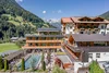 Modernes Hotel in den Bergen mit Außenpool und Terrasse bei sonnigem Wetter