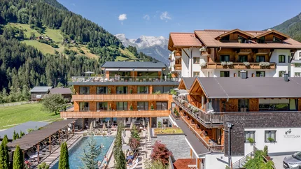 Modern hotel in de bergen met buitenzwembad en terras bij zonnig weer