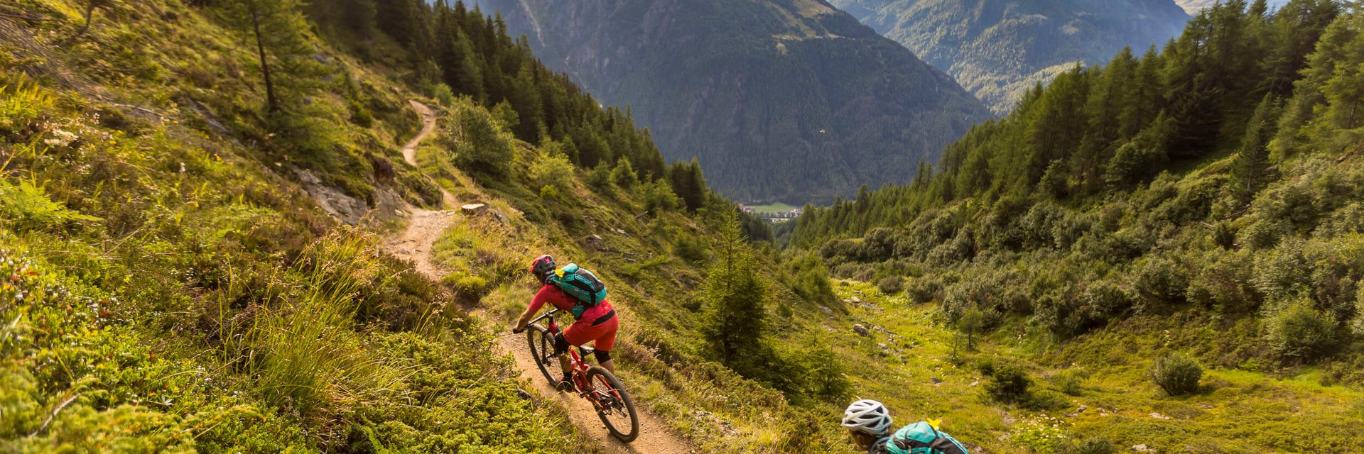 Twee mountainbikers op een bergpad met bergen op de achtergrond