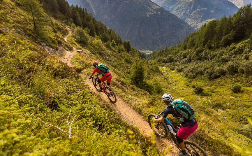 Twee mountainbikers op een bergpad met bergen op de achtergrond