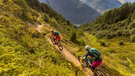 Twee mountainbikers op een bergpad met bergen op de achtergrond