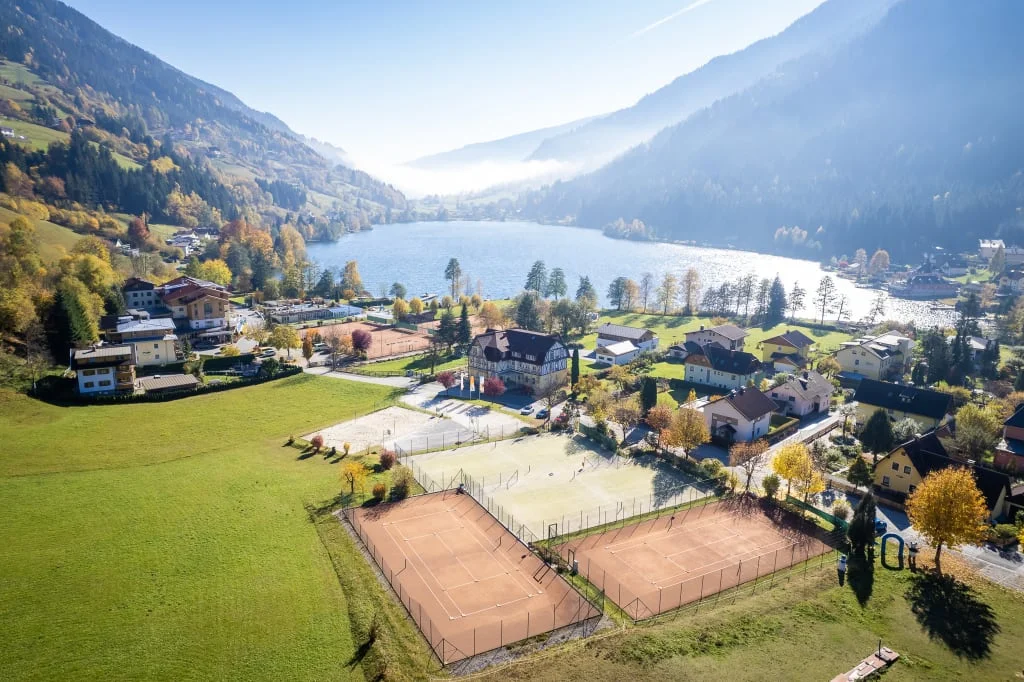 Family Herbst Auszeit 5=4 Bergmeer met dorp, beboste hellingen en tennisbanen op de voorgrond