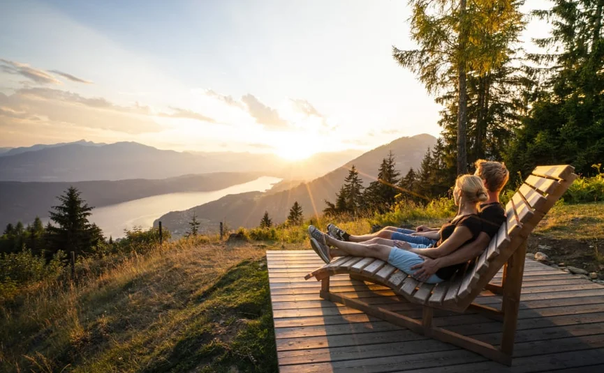 Mountain-Lake experience / 3 nights Two people sitting on wooden benches watching sunset over mountains and lake