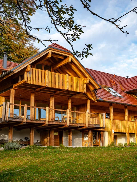 Großes Holzhaus mit Balkon in ländlicher Herbstlandschaft