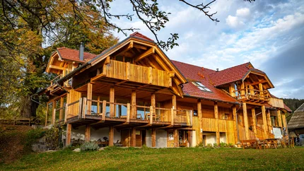 Großes Holzhaus mit Balkon in ländlicher Herbstlandschaft