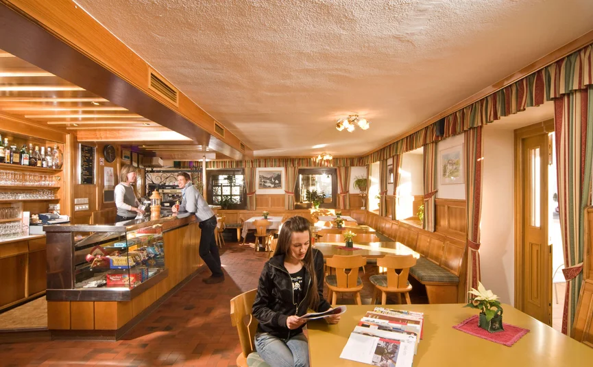 gemütliches café mit kunden an bar und frau liest am tisch