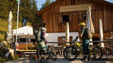 Zwei Mountainbiker vor der Wolfratshauser Hütte an sonnigem Tag