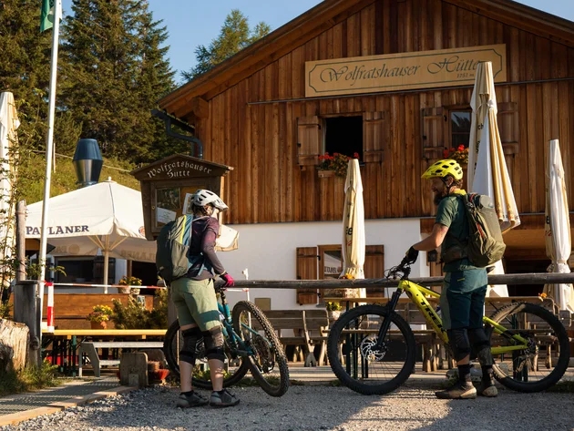 Zwei Mountainbiker vor der Wolfratshauser Hütte an sonnigem Tag