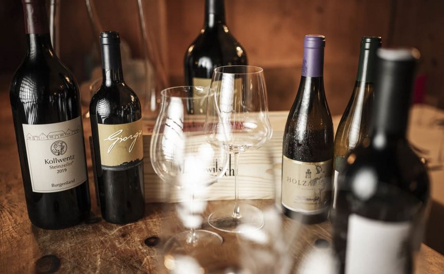 Diverse wijnflessen en lege glazen op een houten tafel