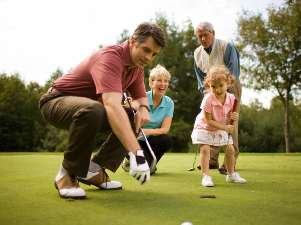 Familie spielt Golf auf dem Grün mit einem kleinen Mädchen und Großeltern