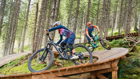 Unterwegs in Österreichs größter Bikeregion © Patrick Wasshuber Zwei Mountainbiker fahren auf Holztrail in bewaldetem Gelände