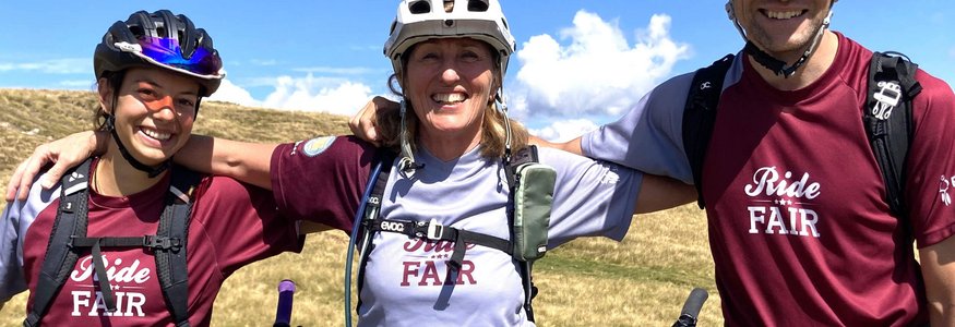Drei Radfahrer in Helmen posieren lächelnd im Freien mit Fahrrädern