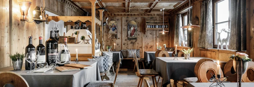 Rustikales Restaurant mit Holzmöbeln, Tischdecken und Weinflaschen