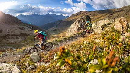 Zwei Mountainbiker fahren auf einem Bergpfad bei sonnigem Wetter