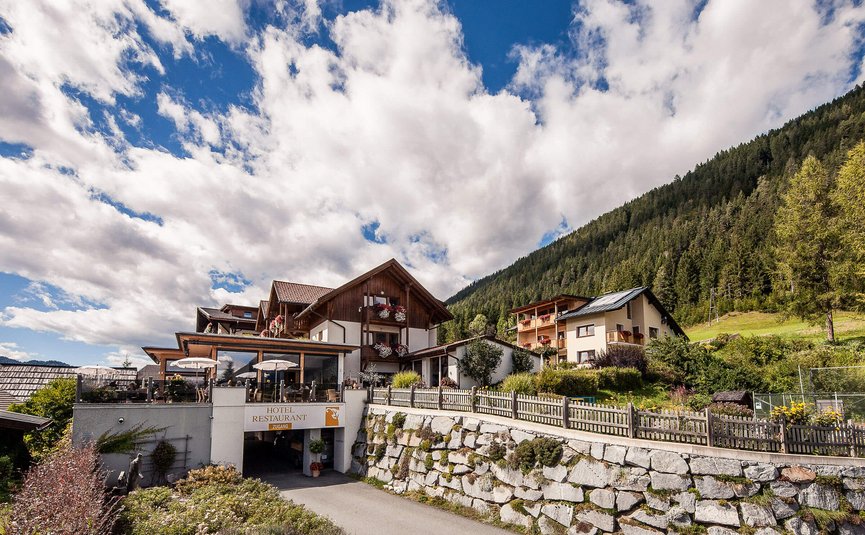 See-Aktivhotel Regitnig - Hotel & Chalets **** © Regitnig GmbH Hotelrestaurant in den Bergen mit sonniger Terrasse und bewaldetem Hügel im Hintergrund