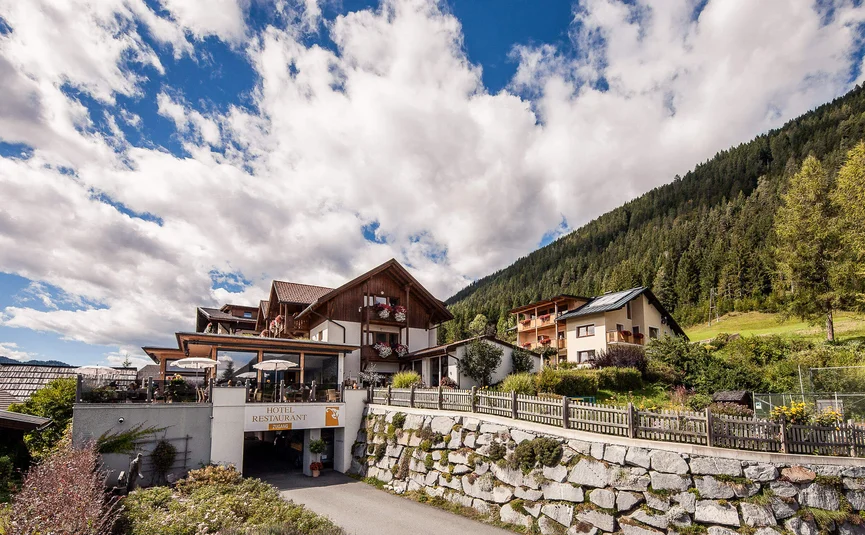 Hotelrestaurant in den Bergen mit sonniger Terrasse und bewaldetem Hügel im Hintergrund