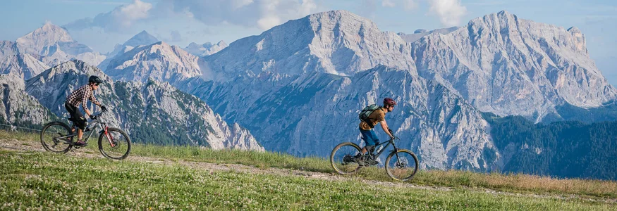 Die Legende Herrnsteig © Harald Wisthaler Zwei Mountainbiker fahren auf einem Bergweg mit Alpen im Hintergrund