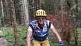 Mann fährt Mountainbike auf Waldweg mit grünen Bäumen