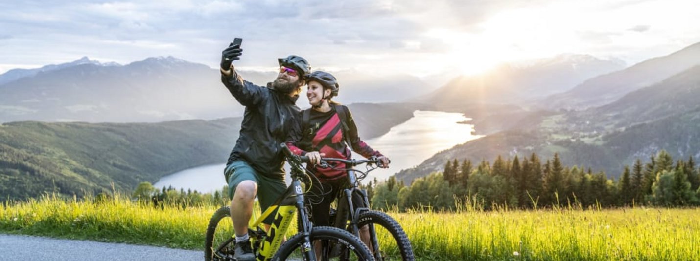 Nockbike-Hit Twee fietsers maken selfie met berg- en meerzicht bij zonsondergang