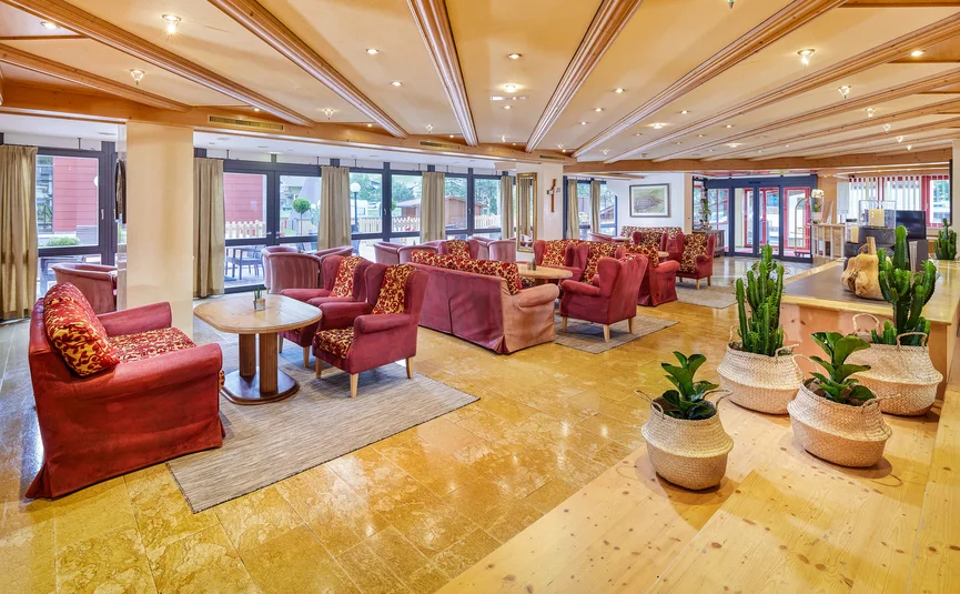 Spacious hotel lounge with red armchairs and potted plants in baskets