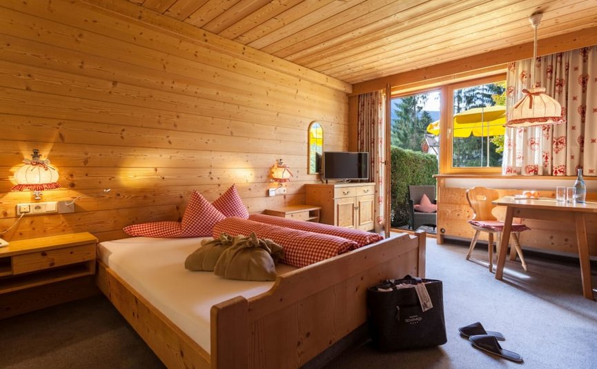 Gezellige houten slaapkamer met tweepersoonsbed en toegang tot balkon