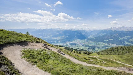 Twee mountainbikers op een bergpad met uitzicht op de Alpen