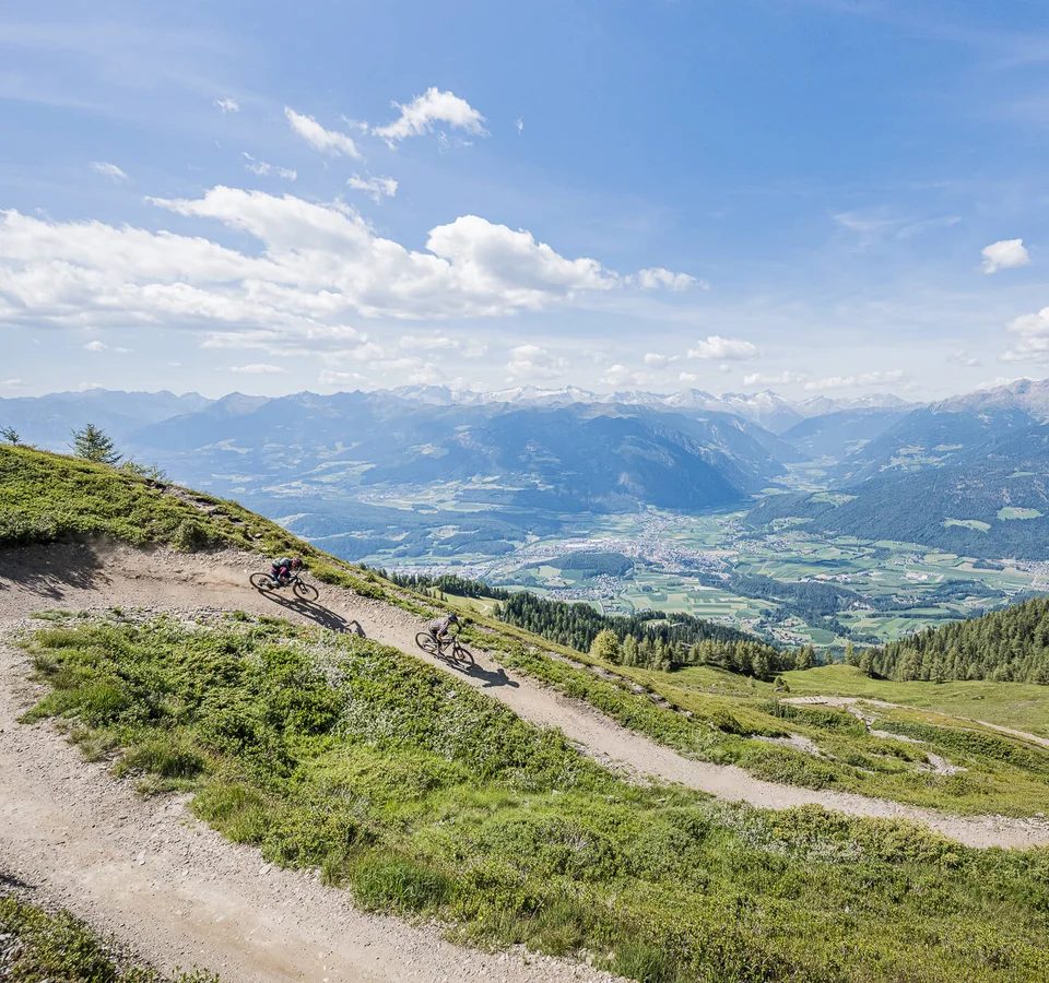 Die Legende Herrnsteig © Harald Wisthaler Zwei Mountainbiker fahren auf einem Bergpfad mit Alpenpanorama