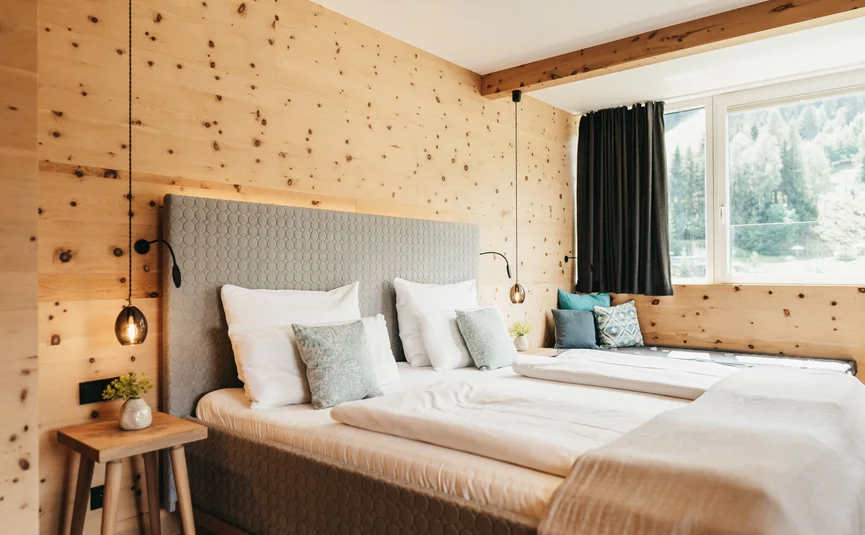 Gemütliches Schlafzimmer mit Holzvertäfelung und großen Fenstern mit Bergblick