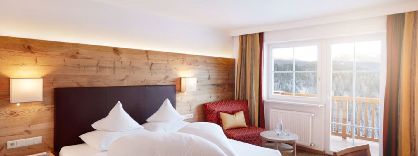 Gezellige hotelkamer met tweepersoonsbed, houten decor en balkon met uitzicht op bergen