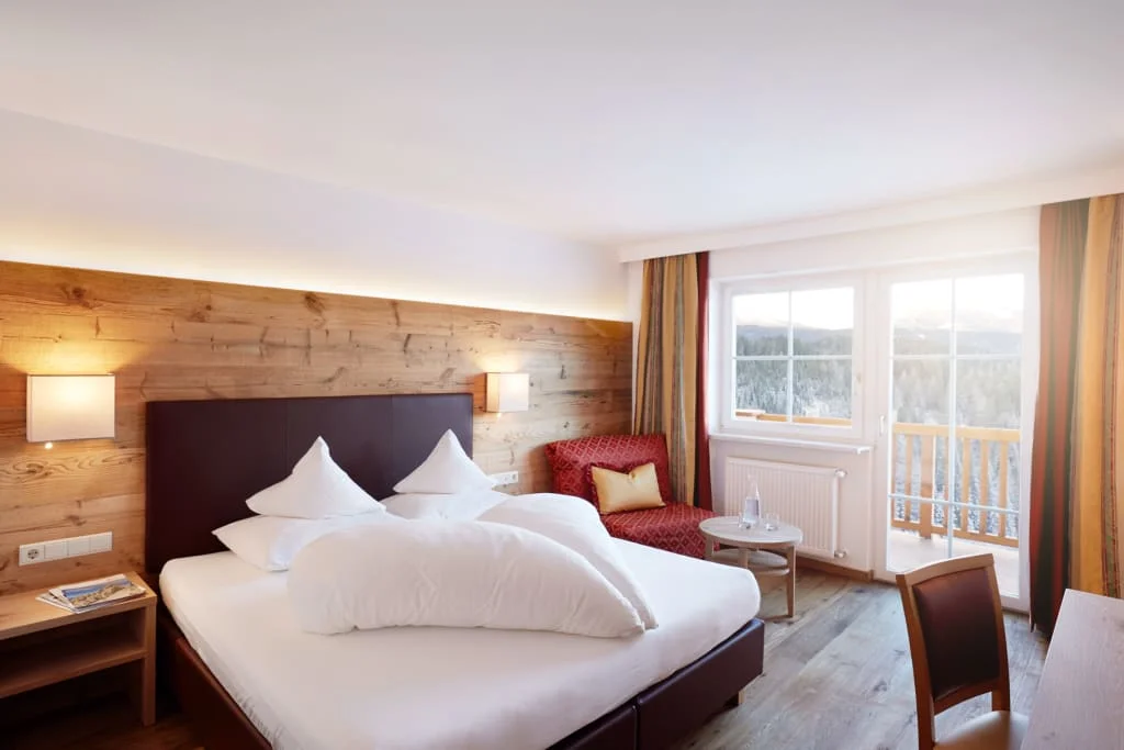 Gezellige hotelkamer met tweepersoonsbed, houten decor en balkon met uitzicht op bergen