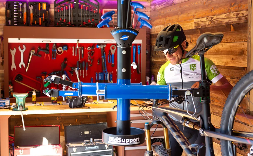 Bike mechanic repairing a mountain bike in a workshop full of tools