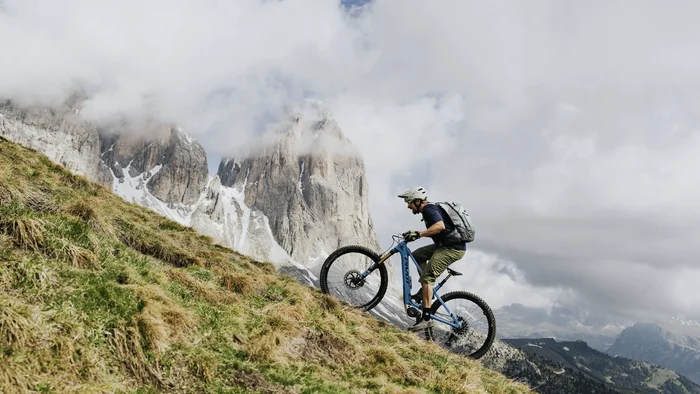 #Uphillflow – der Spaß beginnt schon bergauf © Bosch eBike Systems Mountainbiker fährt einen alpinen Hang hinauf, vor wolkenverhangenen Felsgipfeln