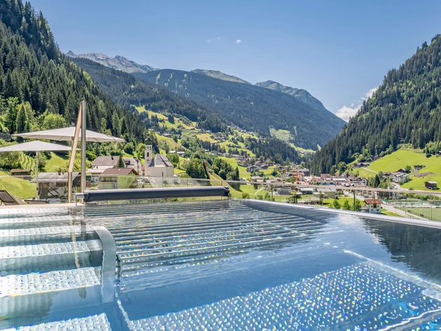 Infinity pool overlooking a valley and forested mountains under a clear sky