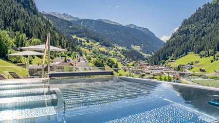 Infinity pool overlooking a valley and forested mountains under a clear sky