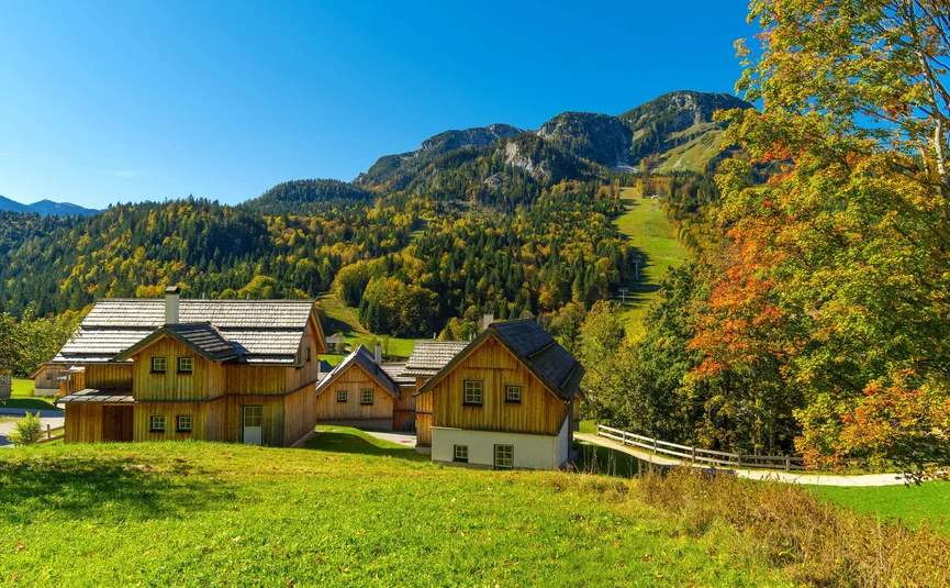 Houten huizen met beboste bergen en blauwe lucht in de herfst