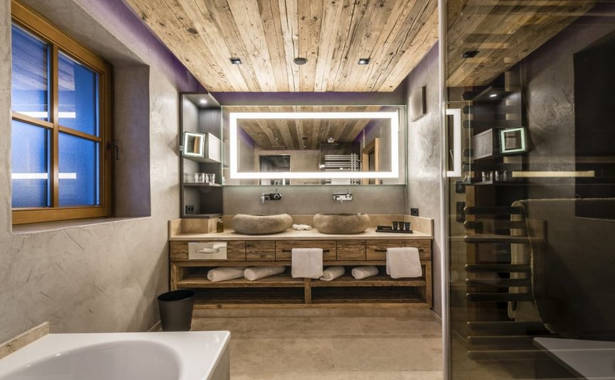 Modern bathroom with wooden ceiling, double sinks, and illuminated mirror