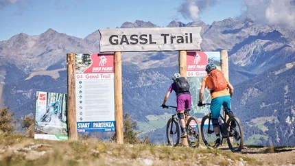 Two mountain bikers starting on Gassl Trail with mountain background
