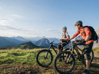 Two mountain bikers resting in the mountains at sunset