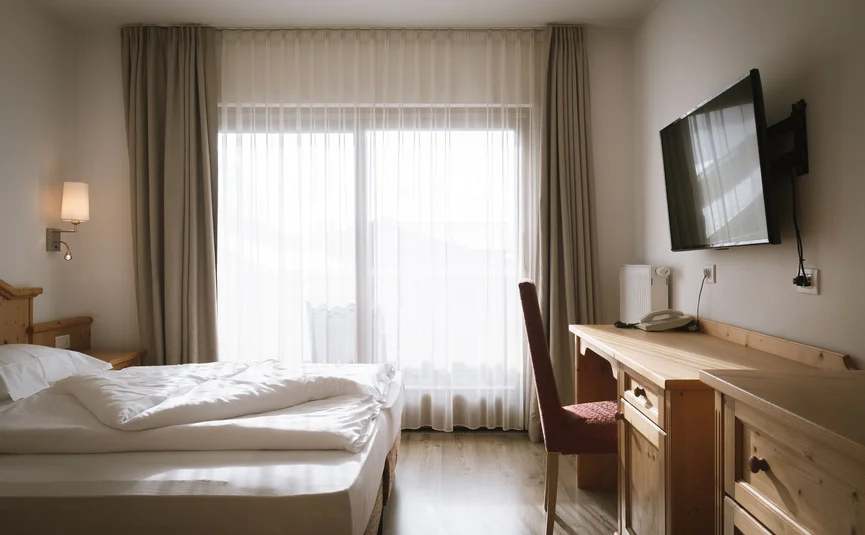 Hotel Innerhofer *** © Lunah Photo & Design Helles Hotelzimmer mit Bett, Schreibtisch, Stuhl und Wandfernseher