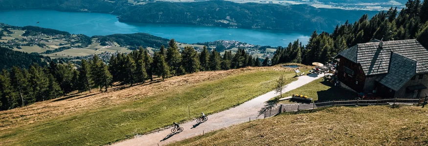 Twee fietsers op bergpad met uitzicht op meer en bergen