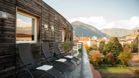 Balcony with three lounge chairs against wooden wall with mountain view