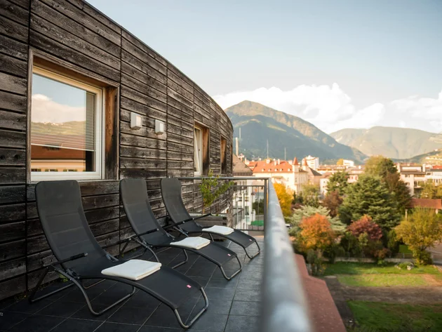 Balcony with three lounge chairs against wooden wall with mountain view