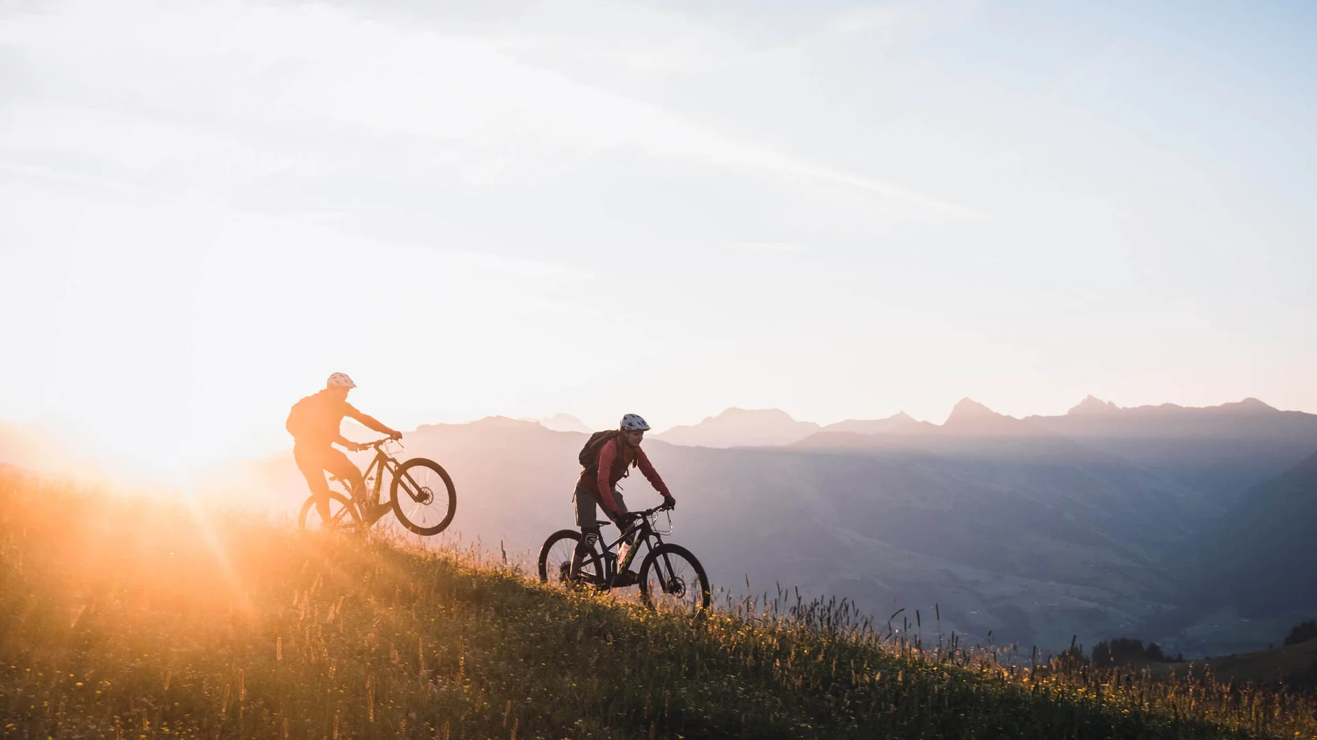 Neuer Flow im Brixental: Der Kirchberg Trail eröffnet © Norman Bielig Zwei Mountainbiker bei Sonnenaufgang in den Bergen