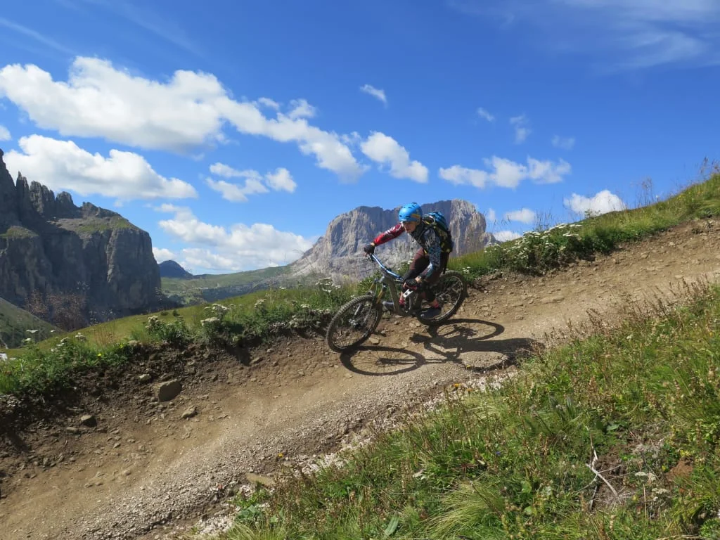 Dolomiten Active for Kids Mountainbiker fährt auf einem Bergweg mit Bergen und blauem Himmel im Hintergrund