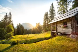 15. Charity Wine & Golf Cup / 3 nights Sunset over a cabin in the forest with two people on a grassy field
