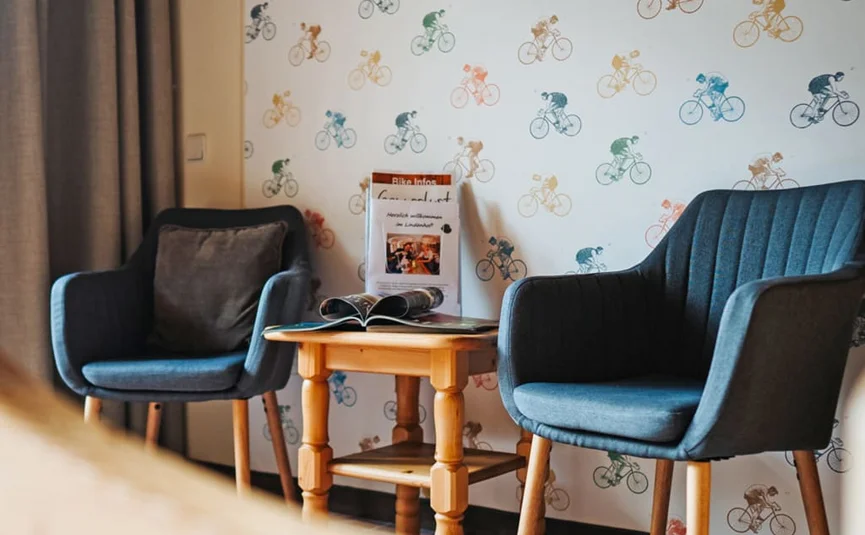 Twee blauwe fauteuils met een houten tafel voor een muur met fietsersbehang