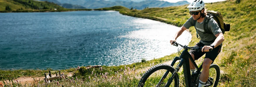 Mit Martina & Flo zum Mountainbiken im LifeSport Hotel Hechenmoos © Martina Wunderle / Flo Distl Mann fährt Mountainbike auf einem Pfad neben einem See in den Bergen